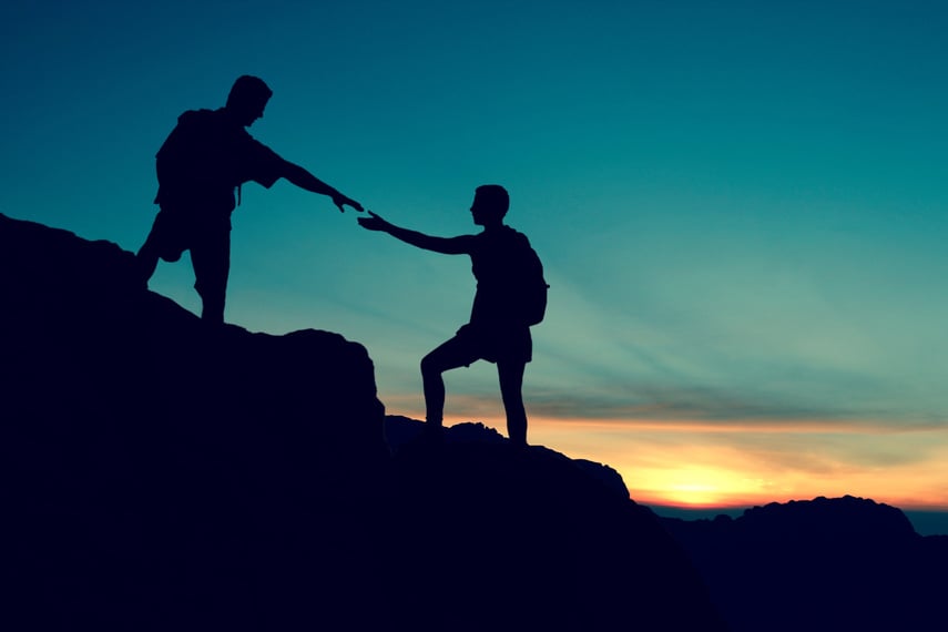 silhouette de deux personnes au sommet d'une montagne au coucher du soleil